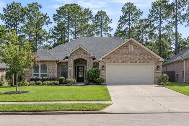 Brick home with a gray shingle roof and pine trees