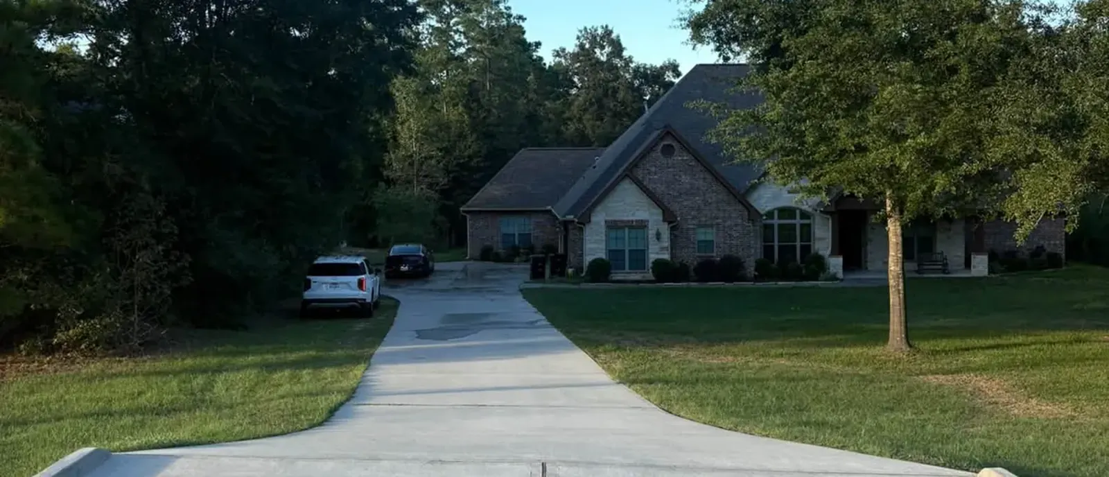 Clean concrete driveway leading up to a brick and stone house