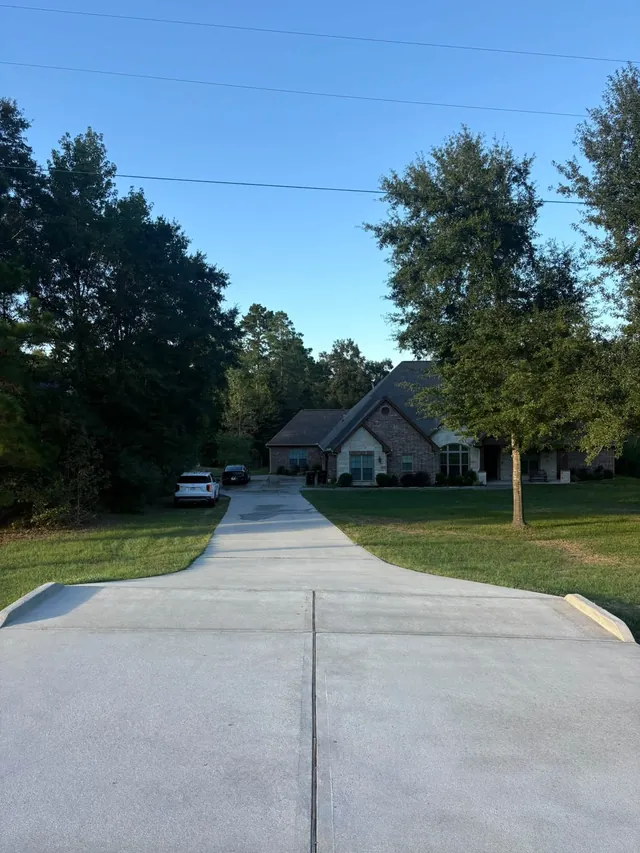 Freshly cleaned concrete driveway leading to a brick house