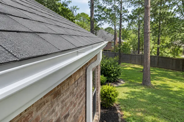 Clean white gutter along a shingle roofline on a brick house
