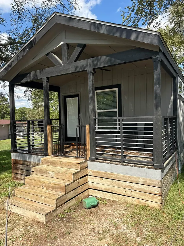 Gray house with a covered porch and wood steps after a full house wash