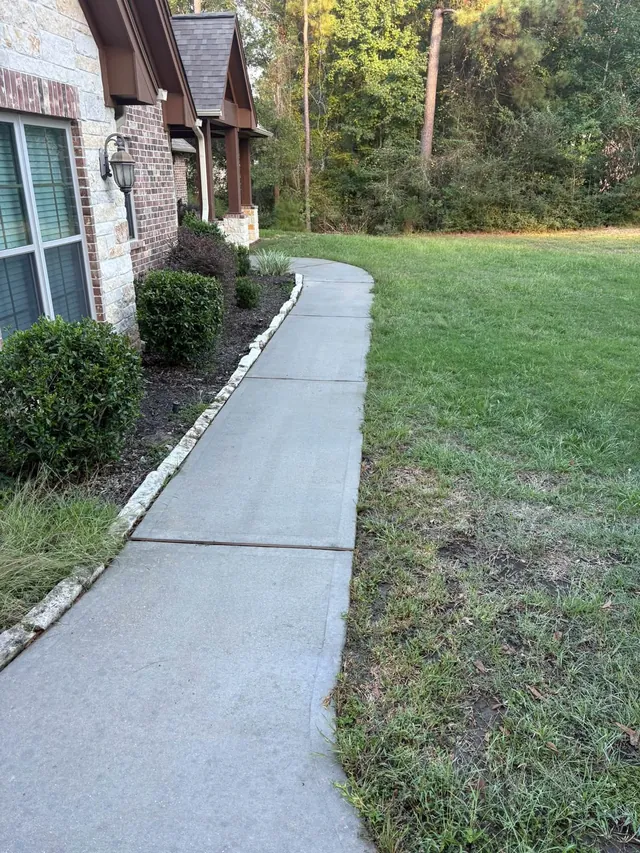 Clean concrete walkway beside a brick house